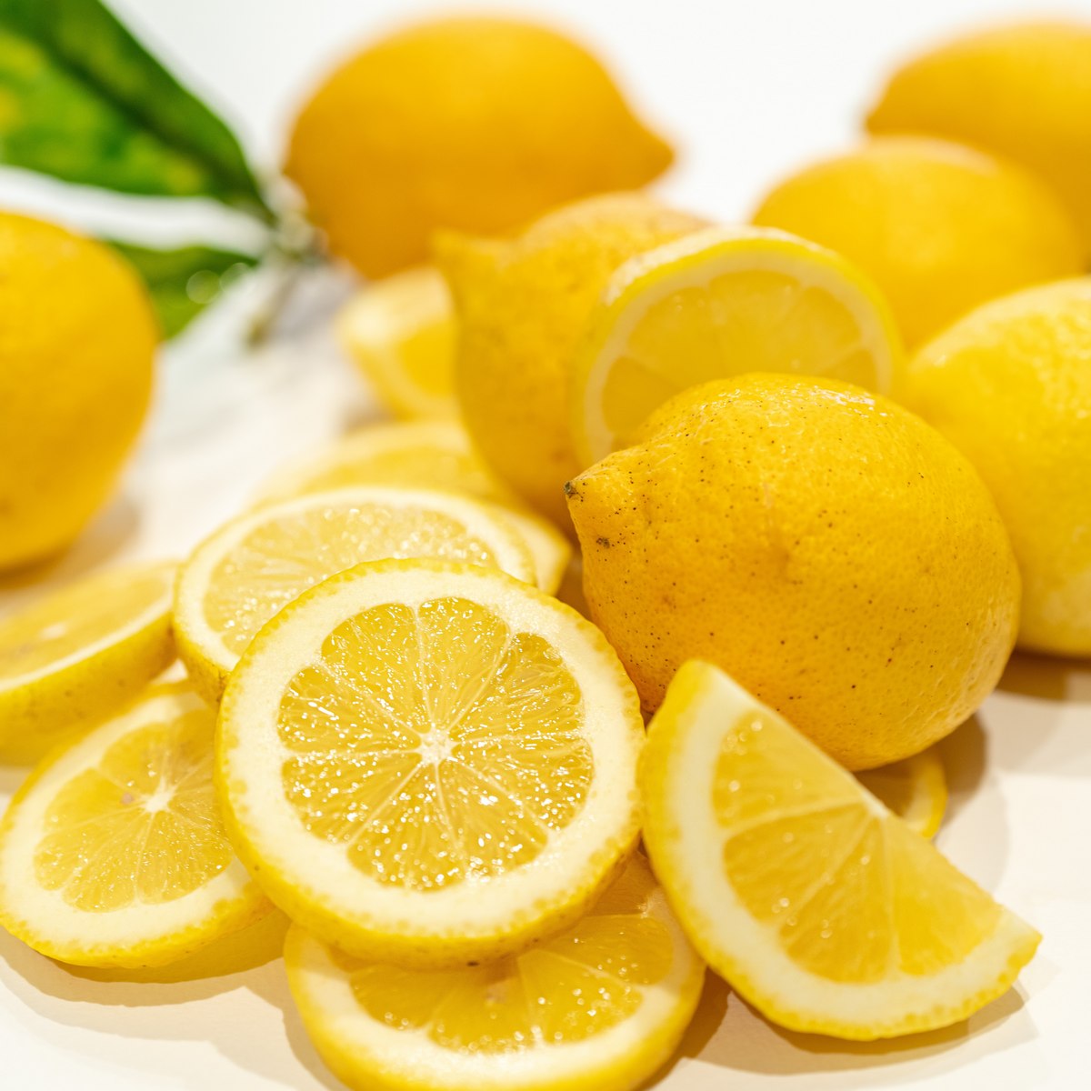 čerstvé celé citrony a nakrájené plátky citronu na bílém pozadí