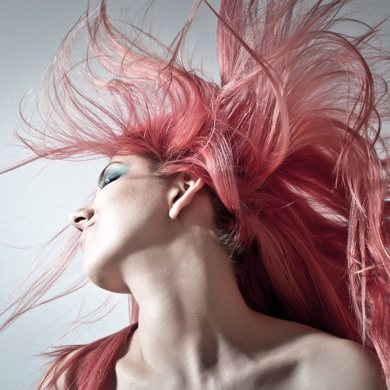 žena s růžovými vlasy rozfoukanými ve vzduchu, zachycená v dramatickém pohybu